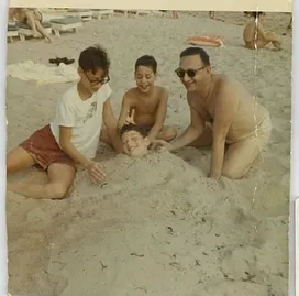Zack with 3 kids on beach, burying Sandy